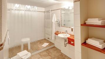 Ein Badezimmer mit Dusche, Toilette, Waschbecken und Handtuchhaltern.