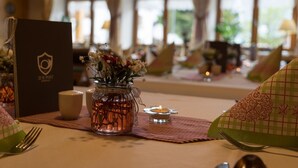 Uma mesa de jantar posta com uma vela, um vaso de flores e um cardápio.
