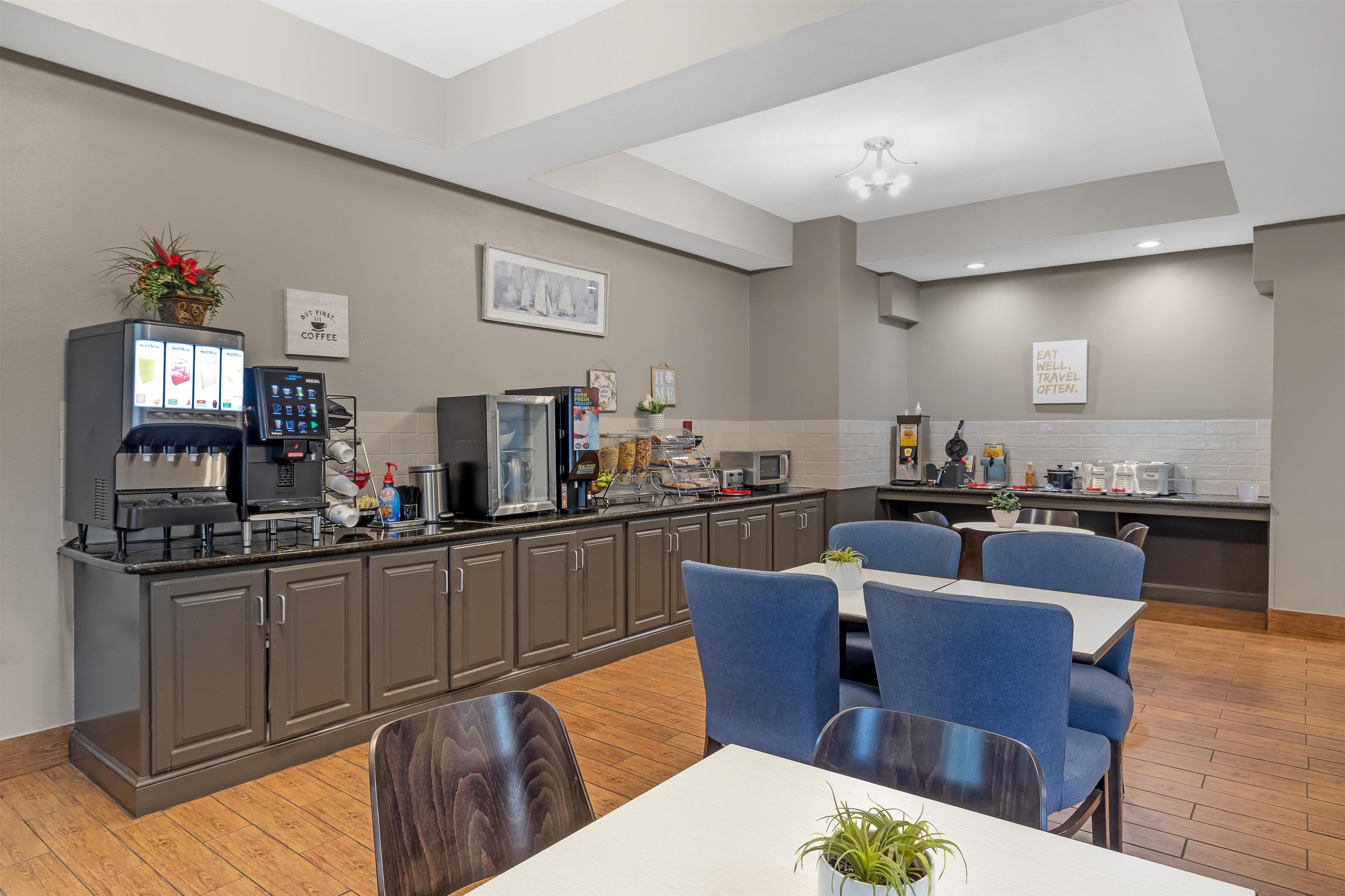 A modern kitchen with a coffee station, seating area, and a view of the dining space.