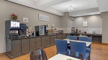 A modern kitchen with a coffee station, seating area, and a view of the dining space.