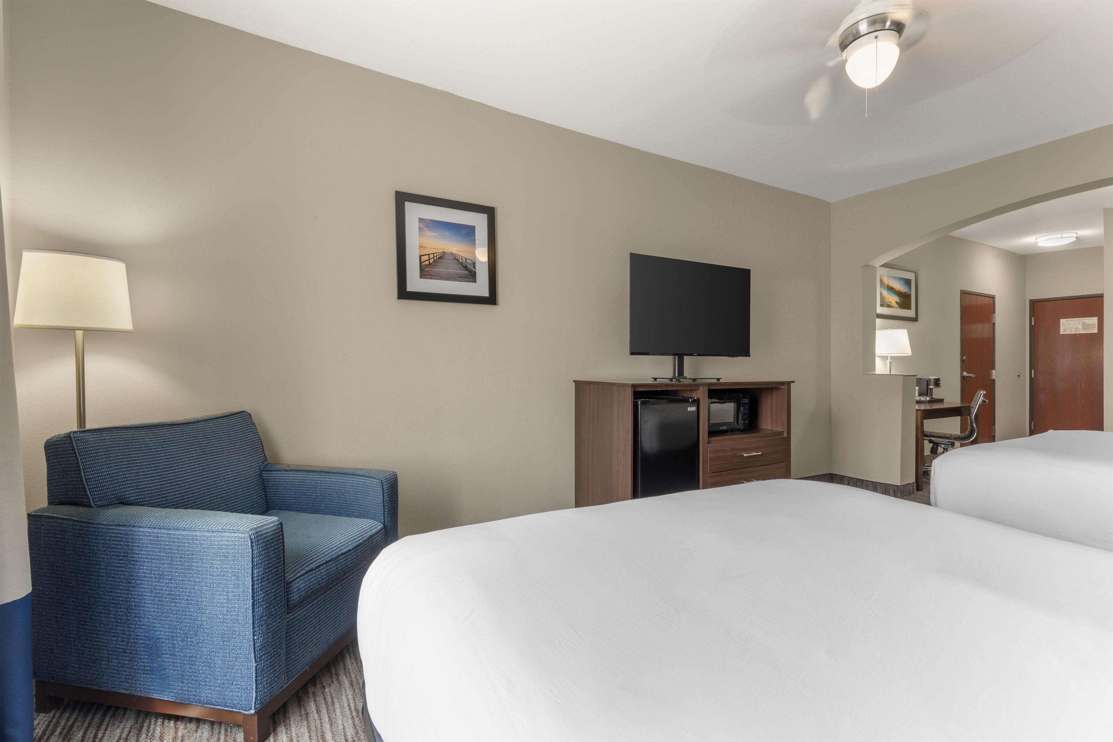 A hotel room with a bed, a television, a desk, a chair, and a picture on the wall.