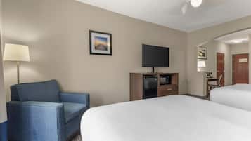 A hotel room with a bed, a television, a desk, a chair, and a picture on the wall.