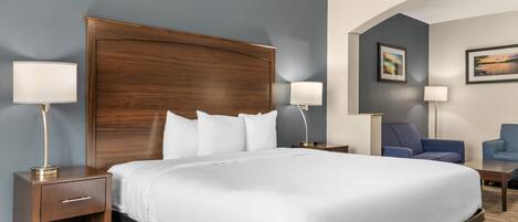 A hotel room with a large bed, two bedside tables, a nightstand, a chair, and two wall-mounted lamps.