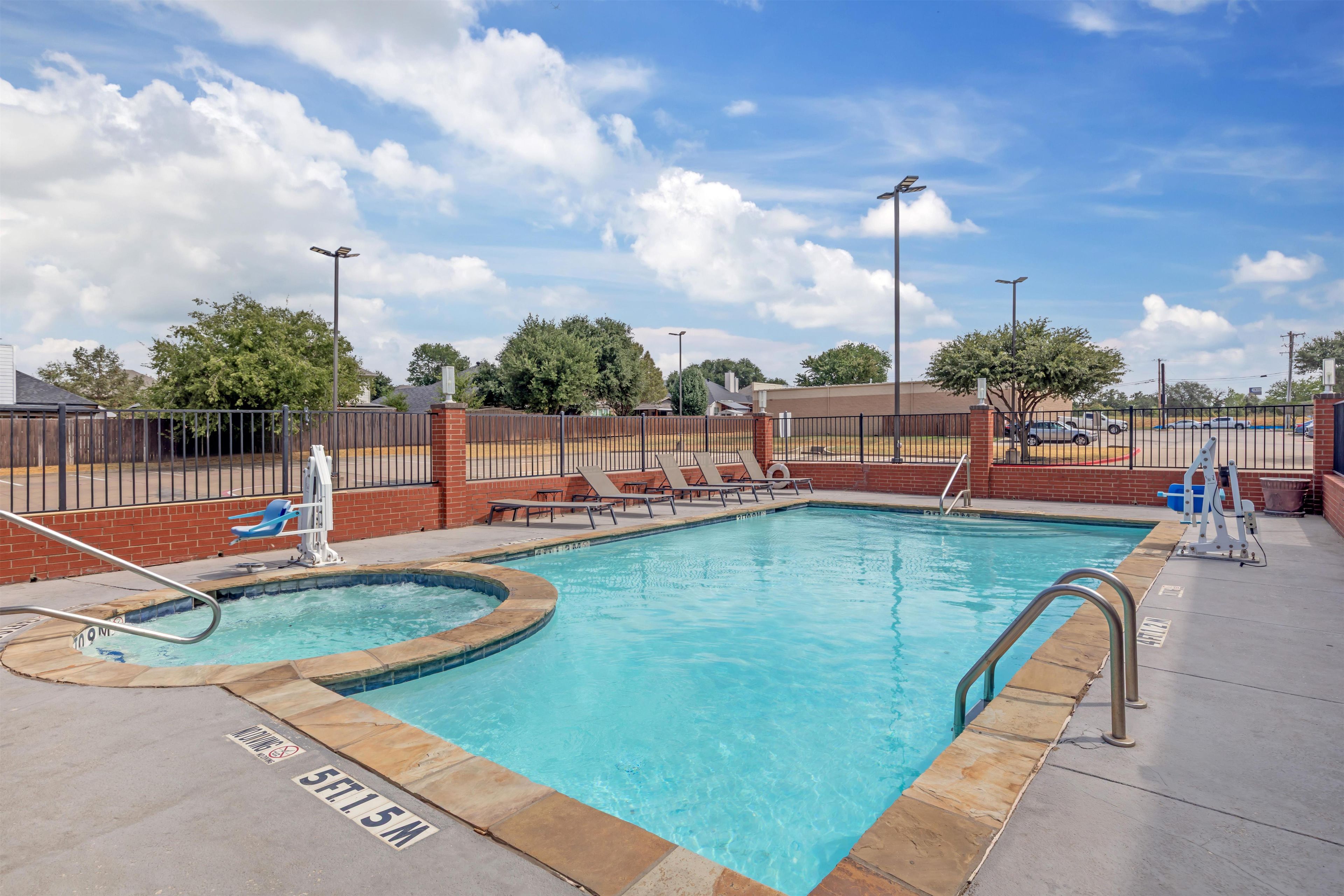 A swimming pool with a sun deck, lounge chairs, and a lifeguard stand.