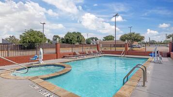 A swimming pool with a sun deck, lounge chairs, and a lifeguard stand.