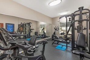A gym with exercise equipment, a mirror, and a blue mat. - Best Western Plus Lake Dallas Inn & Suites (Lake Dallas)