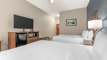 A hotel room with two beds, a flat-screen TV, a microwave, a small table, and a painting on the wall.