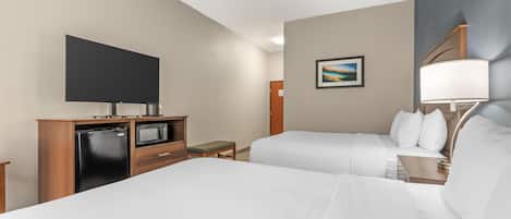 A hotel room with two beds, a flat-screen TV, a microwave, a small table, and a painting on the wall.
