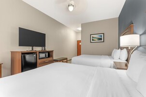 Habitación de hotel con dos camas, un televisor de pantalla plana, microondas, una mesita y un cuadro en la pared.