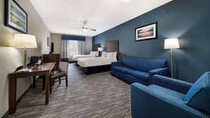 A hotel room with a bed, two bedside tables, a desk, a chair, a sofa, and a standing lamp. - Best Western Plus Lake Dallas Inn & Suites (Lake Dallas)