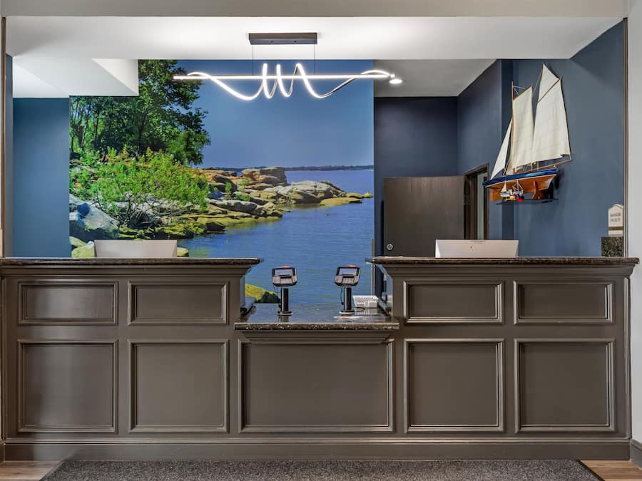 A reception area with a large scenic mural, a wooden desk, a small sailboat model, and a 'Manager on Duty' sign.
