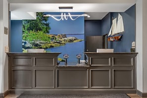 A reception area with a large scenic mural, a wooden desk, a small sailboat model, and a 'Manager on Duty' sign. - Best Western Plus Lake Dallas Inn & Suites (Lake Dallas)