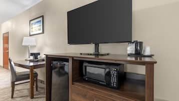 Una habitación de hotel con un escritorio de madera, un microondas, una cafetera y un televisor.