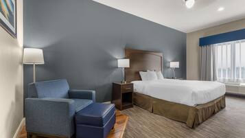 A hotel room with a bed, a chair, a nightstand, and a lamp.