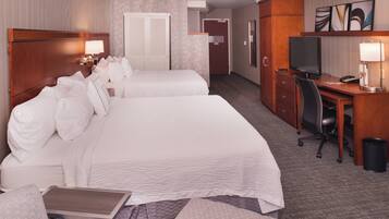 A hotel room with two beds, a desk with a computer, a chair, and a TV.