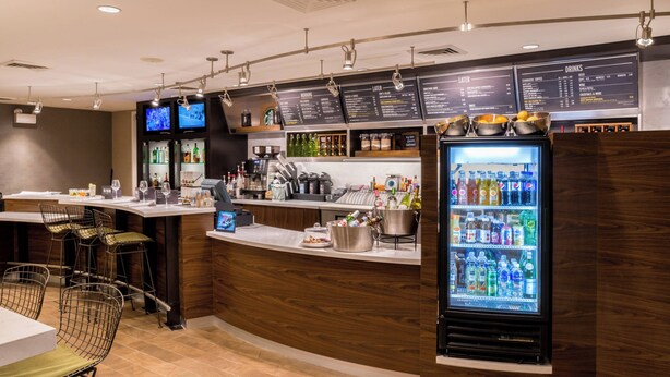 Un espace bar moderne comprenant un comptoir, des sièges et un réfrigérateur pour les boissons.