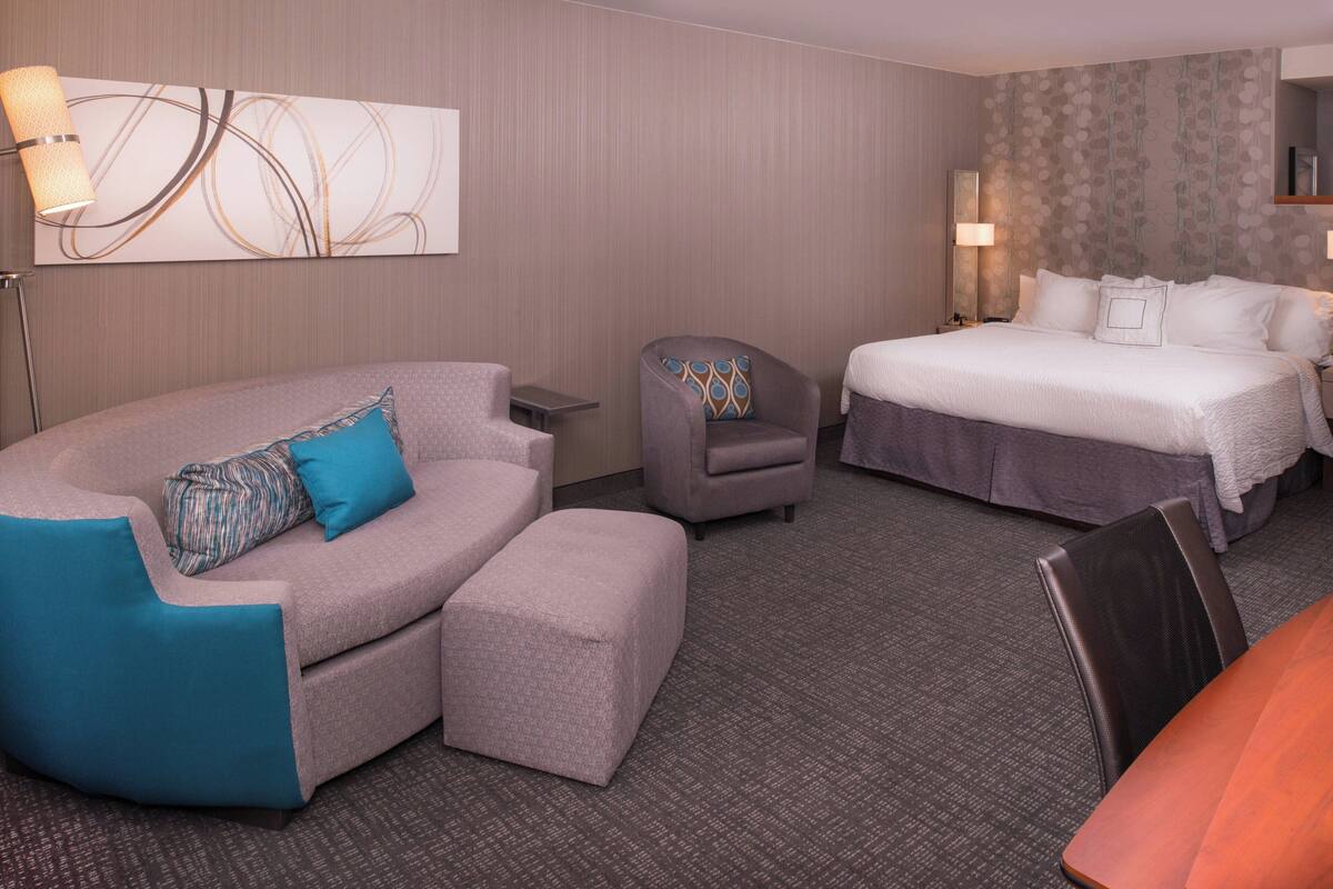 A hotel room with a sofa, armchair, and a bed.