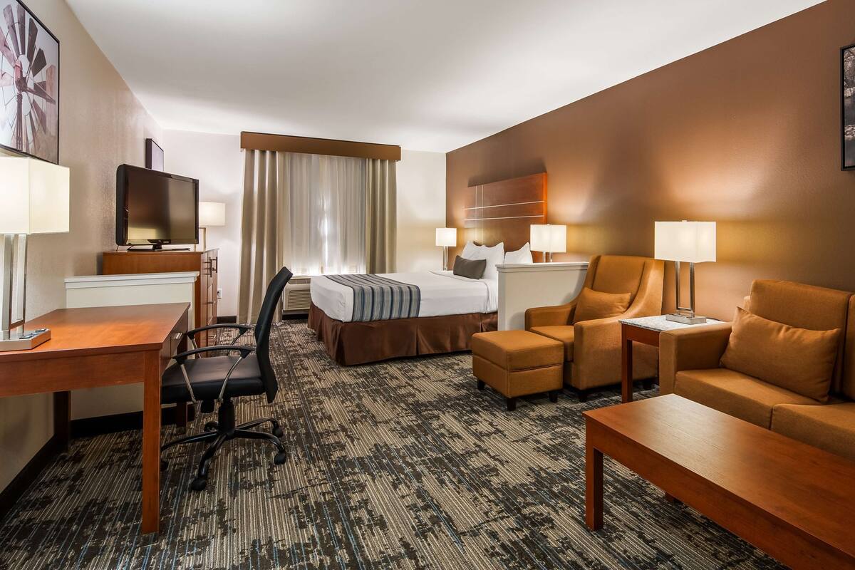 Habitación de hotel con cama, escritorio con computadora, sofá y televisión.