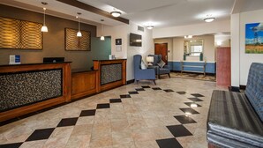 Un'area di accoglienza con reception, una zona relax con divano blu e pavimento decorato.