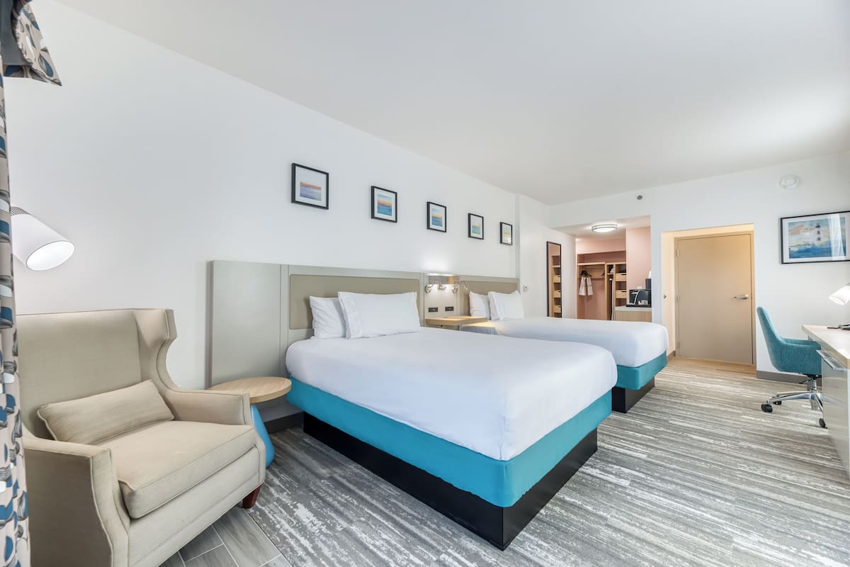 Quarto de hotel com duas camas, um sofá, uma mesa e uma cadeira.