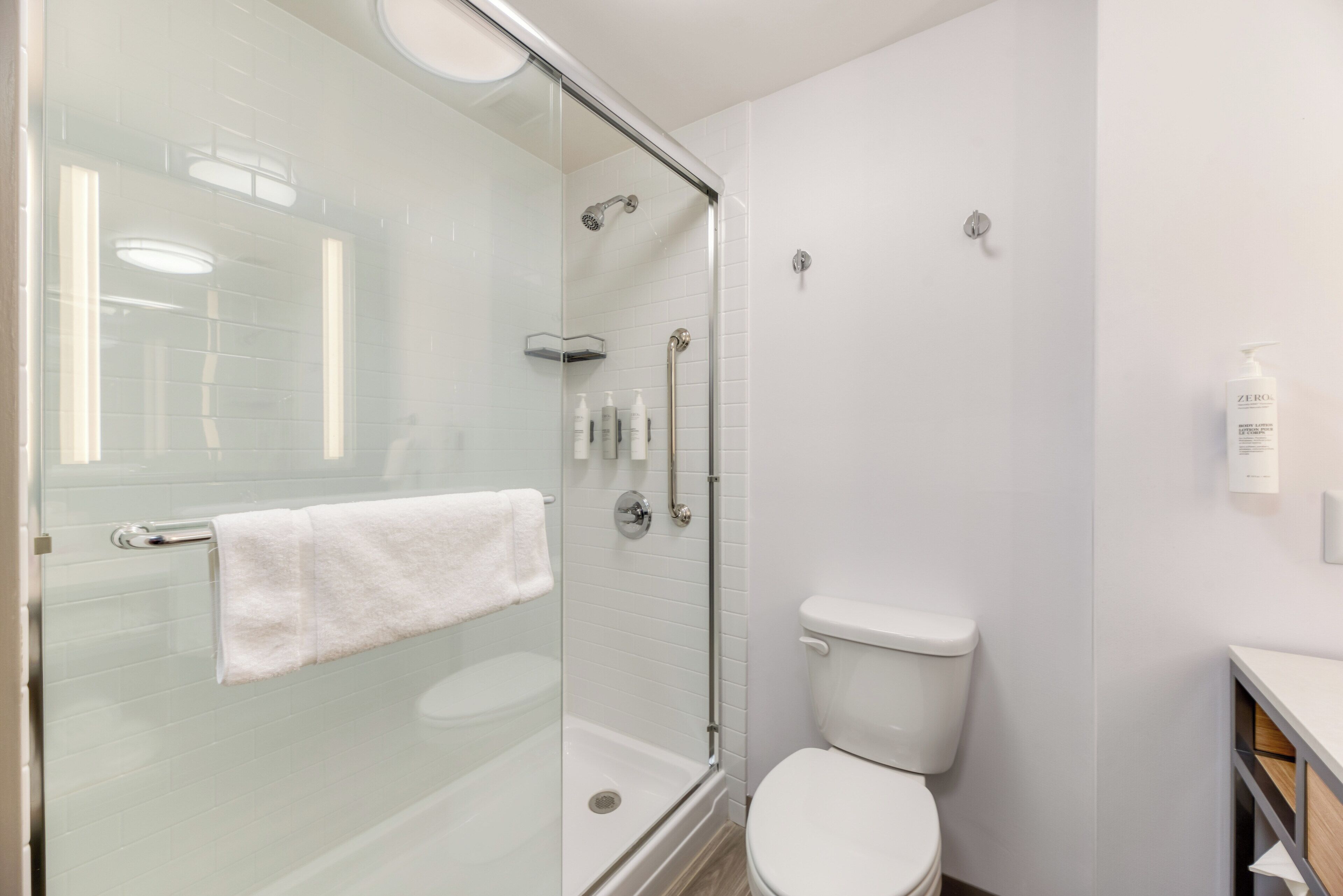 Une salle de bain moderne avec une douche à parois de verre, des toilettes blanches et un porte-serviettes.