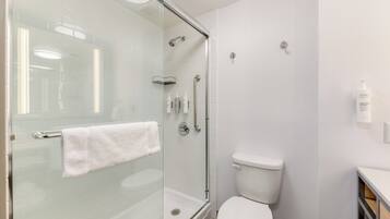 Une salle de bain moderne avec une douche à parois de verre, des toilettes blanches et un porte-serviettes.
