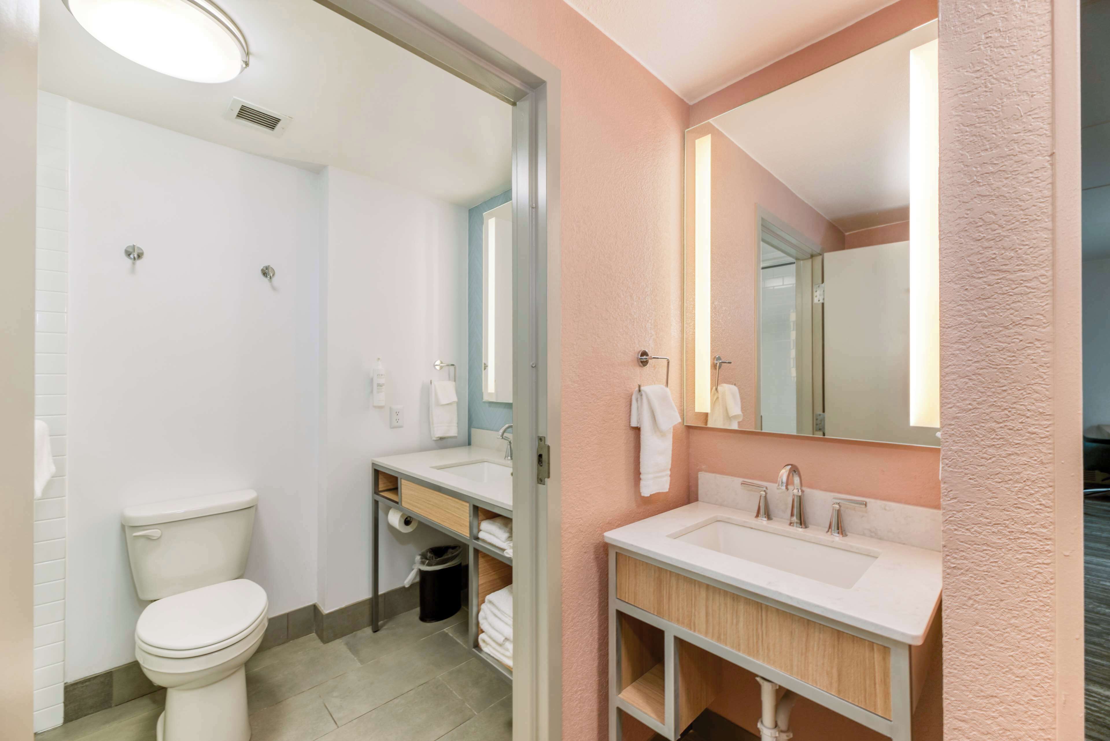 A modern bathroom with a toilet, sink, and mirror.
