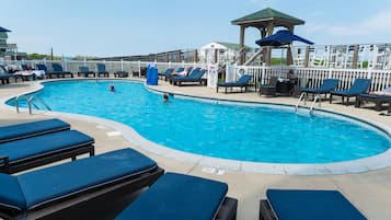 Relax by the pool surrounded by lounge chairs and sunbeds, with a shaded gazebo nearby.