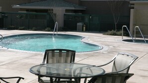 A swimming pool with a circular shape, surrounded by a paved area with chairs and a table. - Holiday Inn Express Hotel & Suites Tehachapi by IHG (Tehachapi)