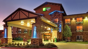 A Holiday Inn Express & Suites building with a covered entrance, stone facade, and illuminated signage. - Holiday Inn Express Hotel & Suites Tehachapi by IHG (Tehachapi)