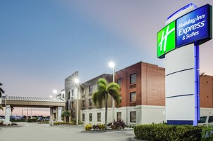 Un hotel Holiday Inn Express & Suites con diseño arquitectónico moderno, que cuenta con una señalización llamativa y un estacionamiento.