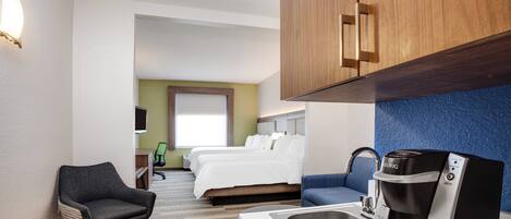 A hotel room with a bed, a desk, a chair, a coffee maker, and a sink.