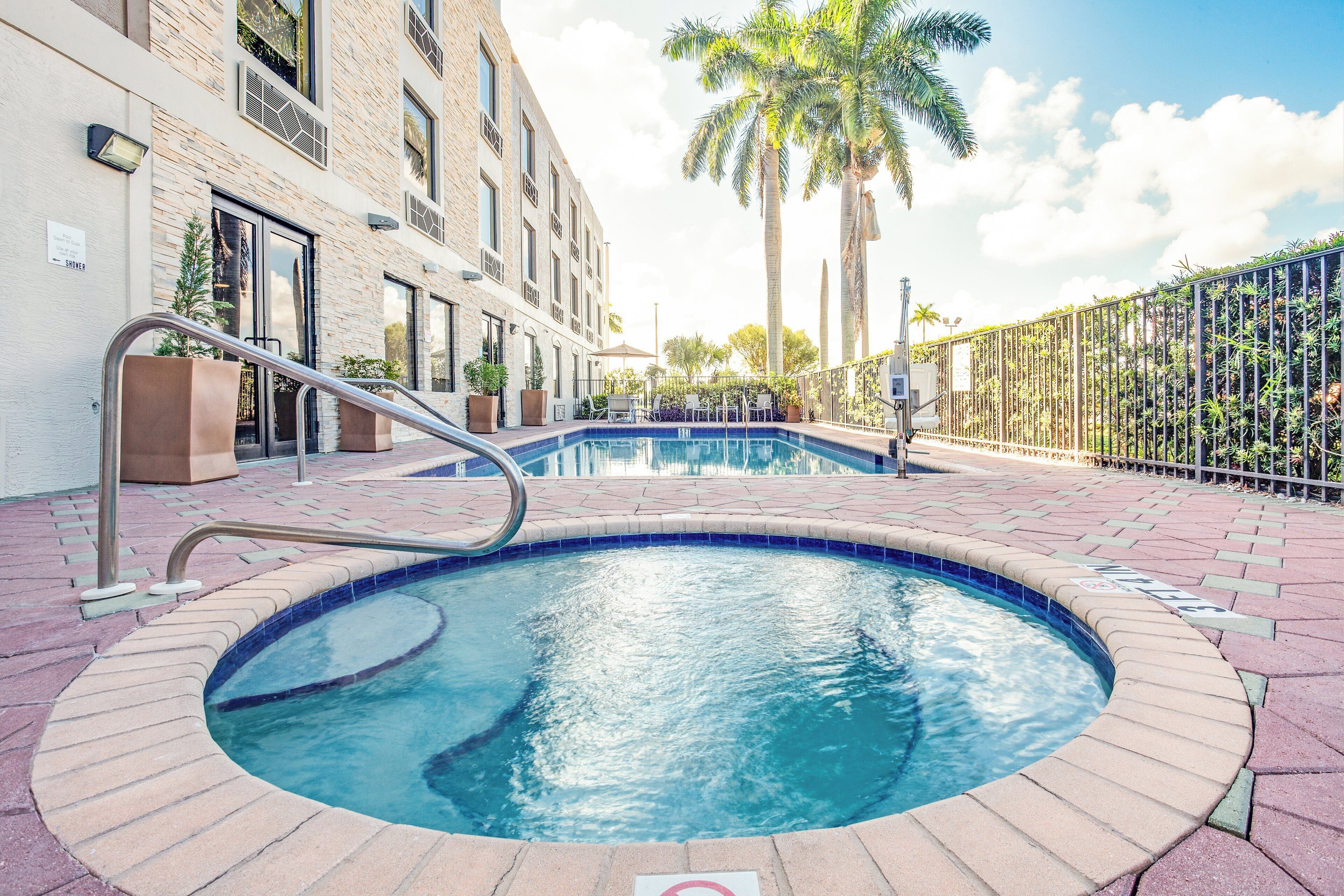 A swimming pool with a metal ladder, surrounded by a brick walkway.