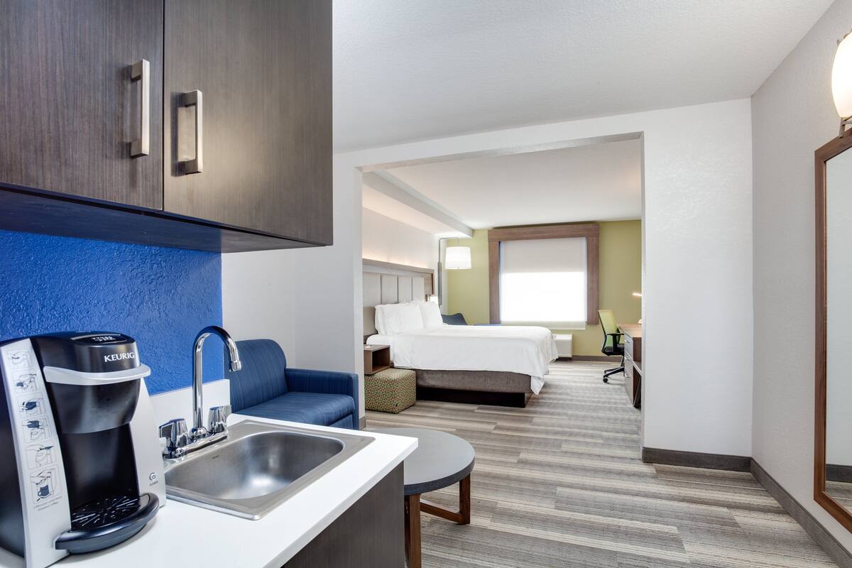 Una habitación de hotel con kitchenette, cama, sofá y escritorio.