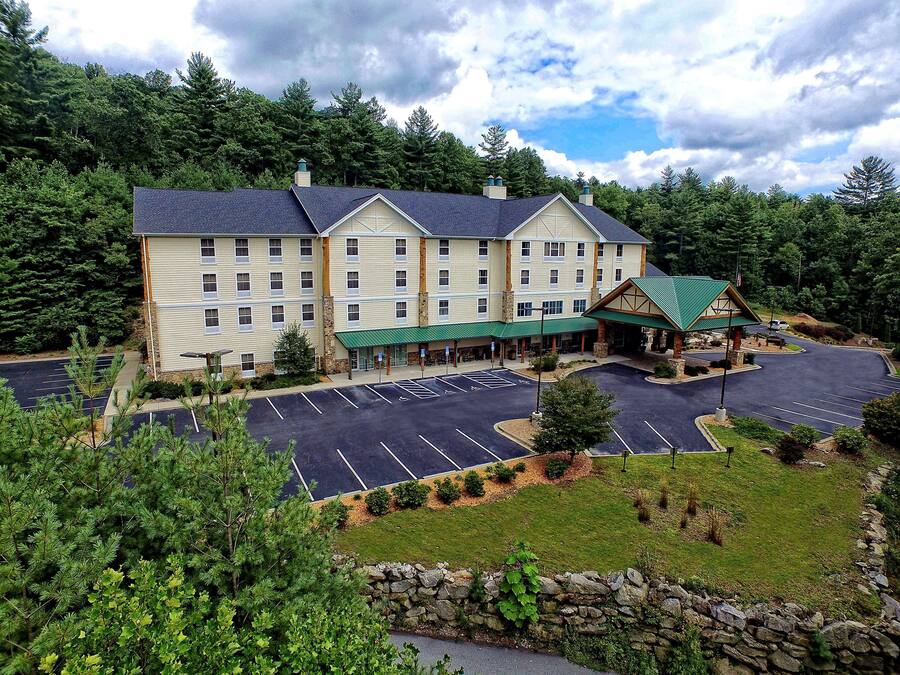 Et stort hotel med grønt tag og parkeringsplads.