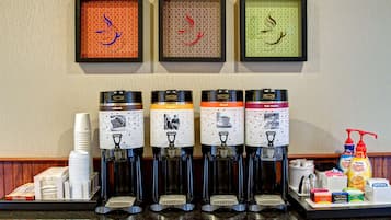 A coffee station with four dispensers, each labeled with different coffee types.