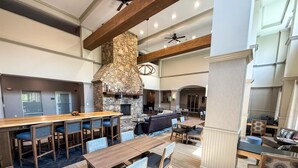 A spacious indoor area with a stone fireplace, wooden bar, and seating arrangements. - Hampton Inn & Suites Cashiers Sapphire Valley (Sapphire)