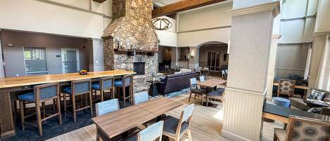 A spacious indoor area with a stone fireplace, wooden bar, and seating arrangements.