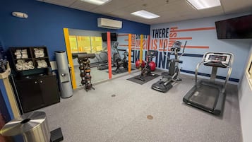 A gym with exercise equipment, a mirror, and a wall with motivational text.