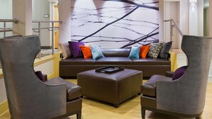 A modern lounge area with a sofa and two armchairs, a coffee table, and a wall with a black and white abstract design. - Hampton Inn Danbury (Danbury)