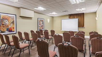 A conference room with rows of chairs, a whiteboard, and two framed artworks on the walls.