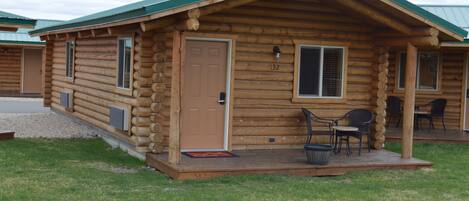 A log cabin with a porch, a door, and a window.