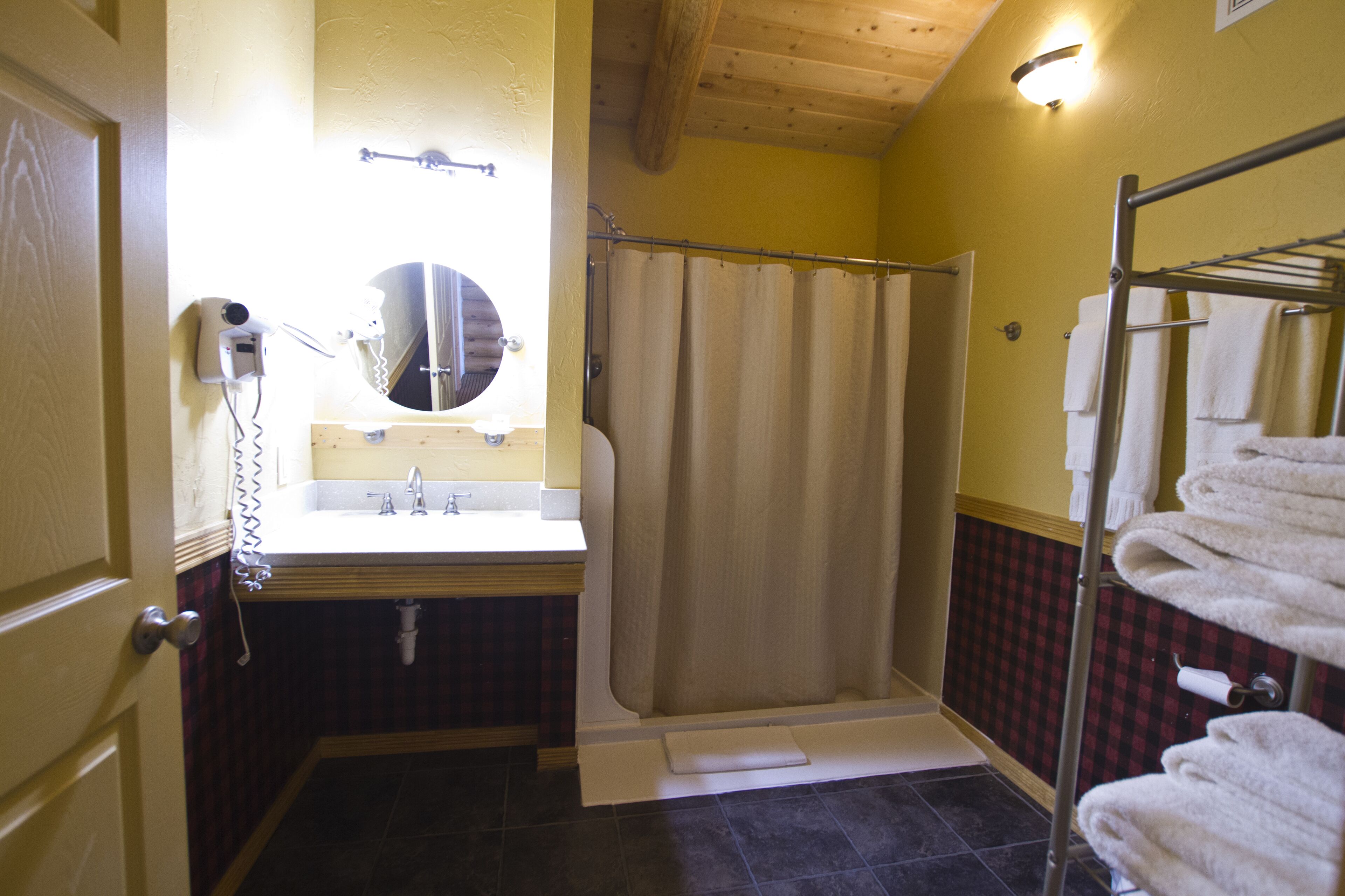 A bathroom with a shower, a sink, a hairdryer, and a towel rack.
