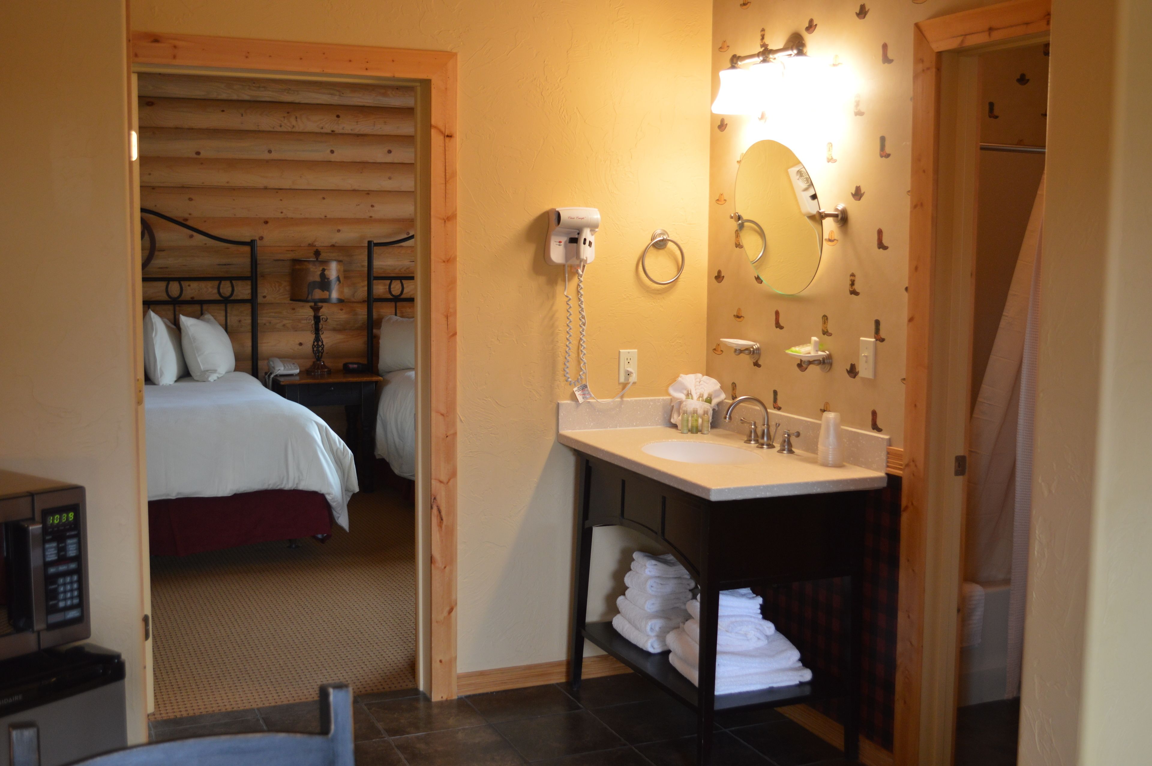 A hotel room with a bed, a bathroom with a sink, and a mirror.