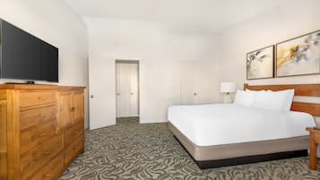 A hotel room with a large bed, wooden dresser, and a flat-screen TV.