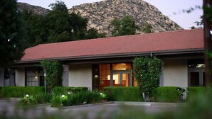 A building with a red-tiled roof, large windows, and a landscaped garden.