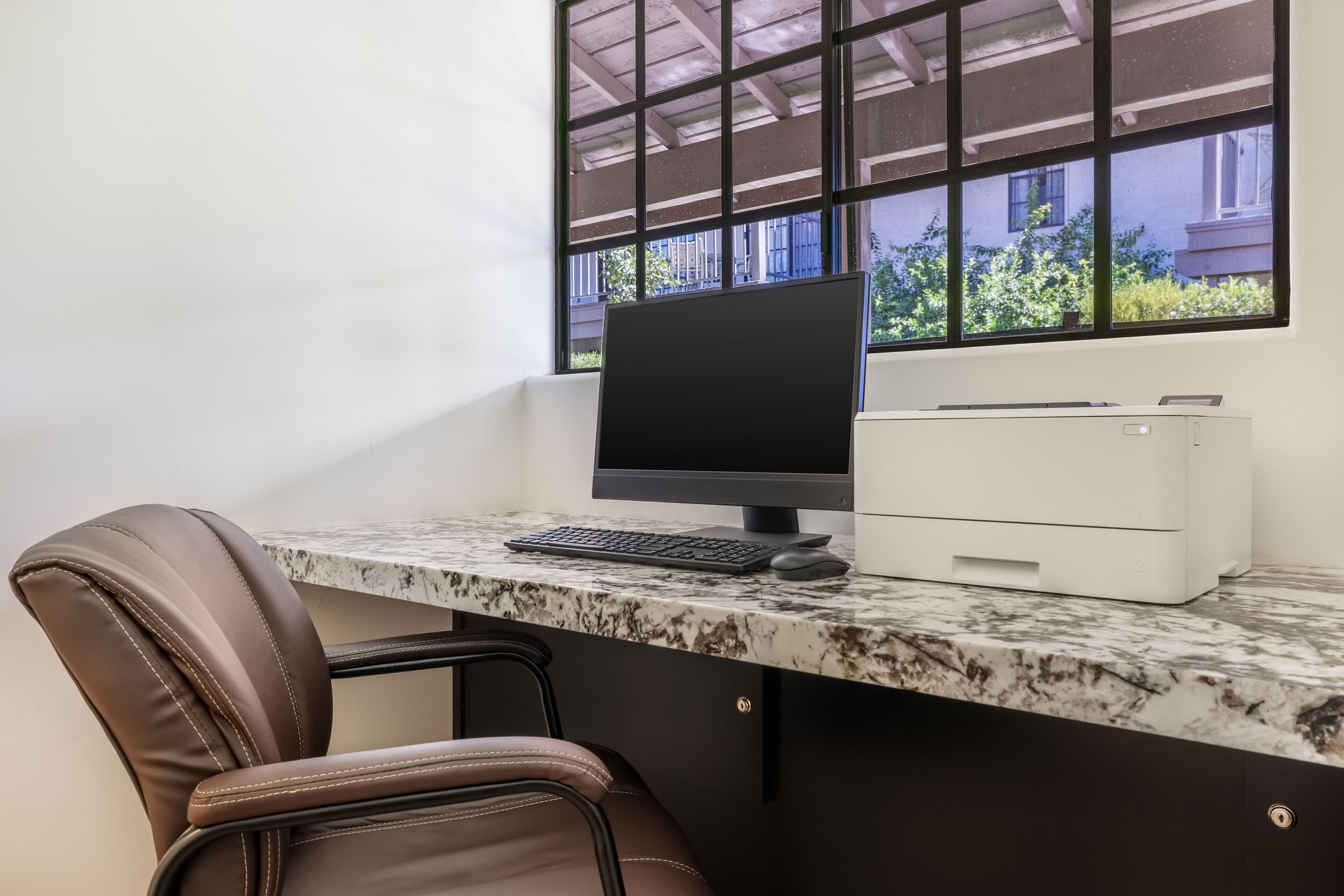 A modern office desk with a computer, keyboard, and printer.