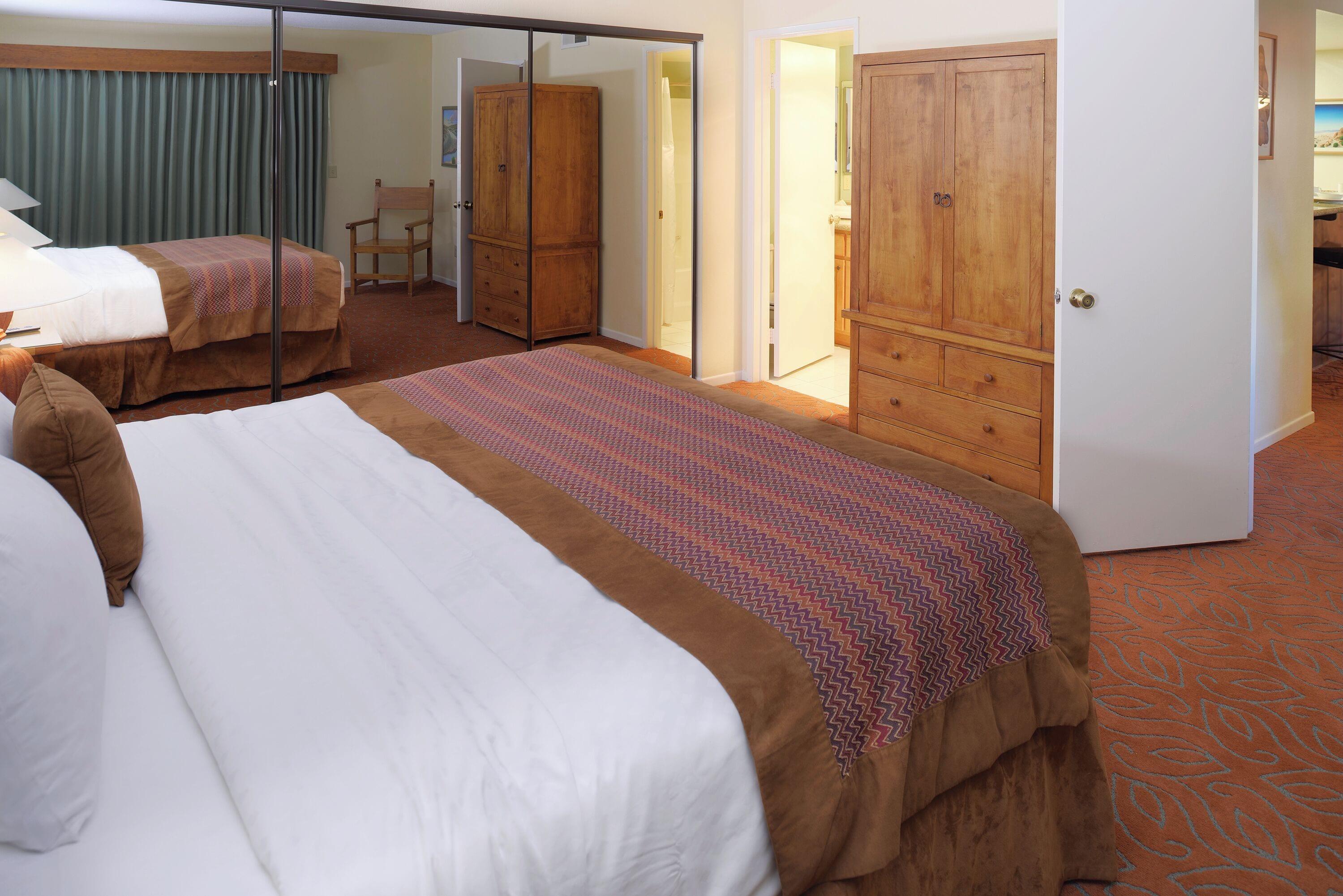 Habitación de hotel con dos camas, un armario y un espejo.