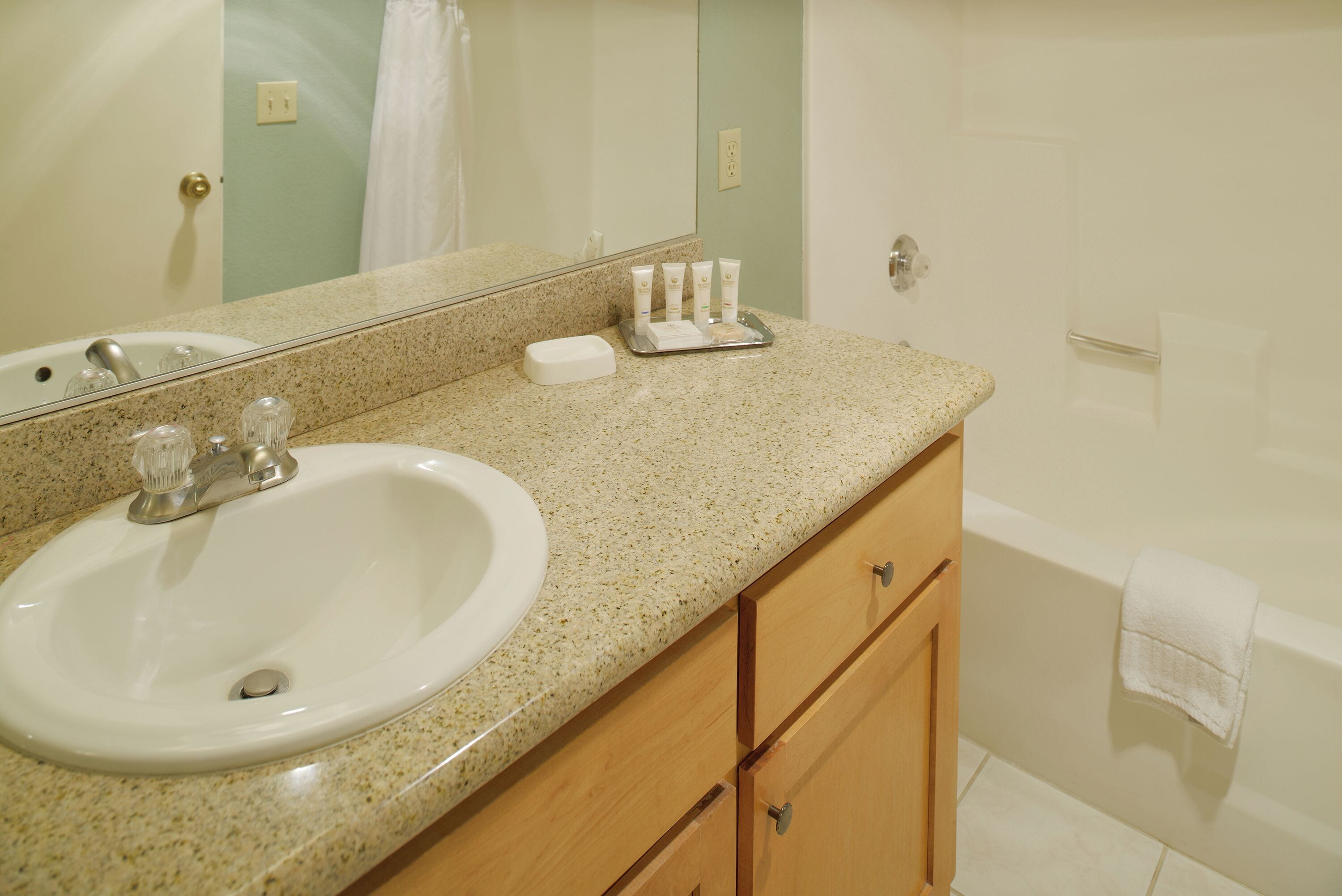 A bathroom with a sink, mirror, and toiletries on the counter.