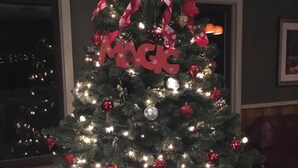 A Christmas tree decorated with lights, ornaments, and a bow. - The Upper Pass Lodge at Magic Mountain (Londonderry)